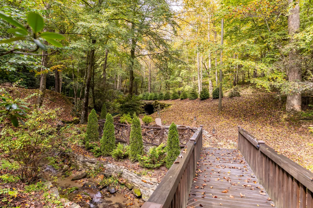 A scenic exterior featuring a wooden bridge, stone wall, and a lush, green pathway surrounded by mature trees. The environment is calm and inviting, with opportunities for gentle walks, nature observation, and quiet reflection—ideal for romantic exploration or peaceful strolls.